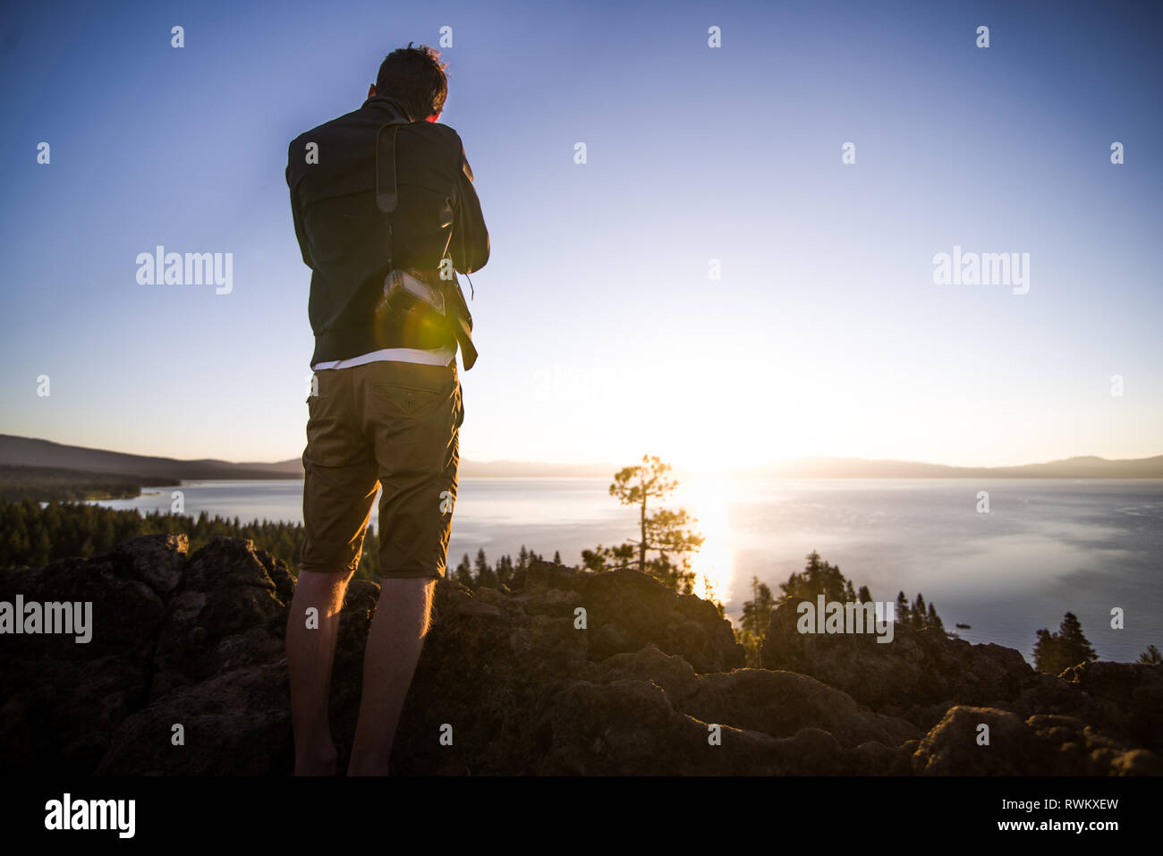 Man taking photographs at sunrise, Lake Tahoe, Tahoe City, California, United States Stock Photo