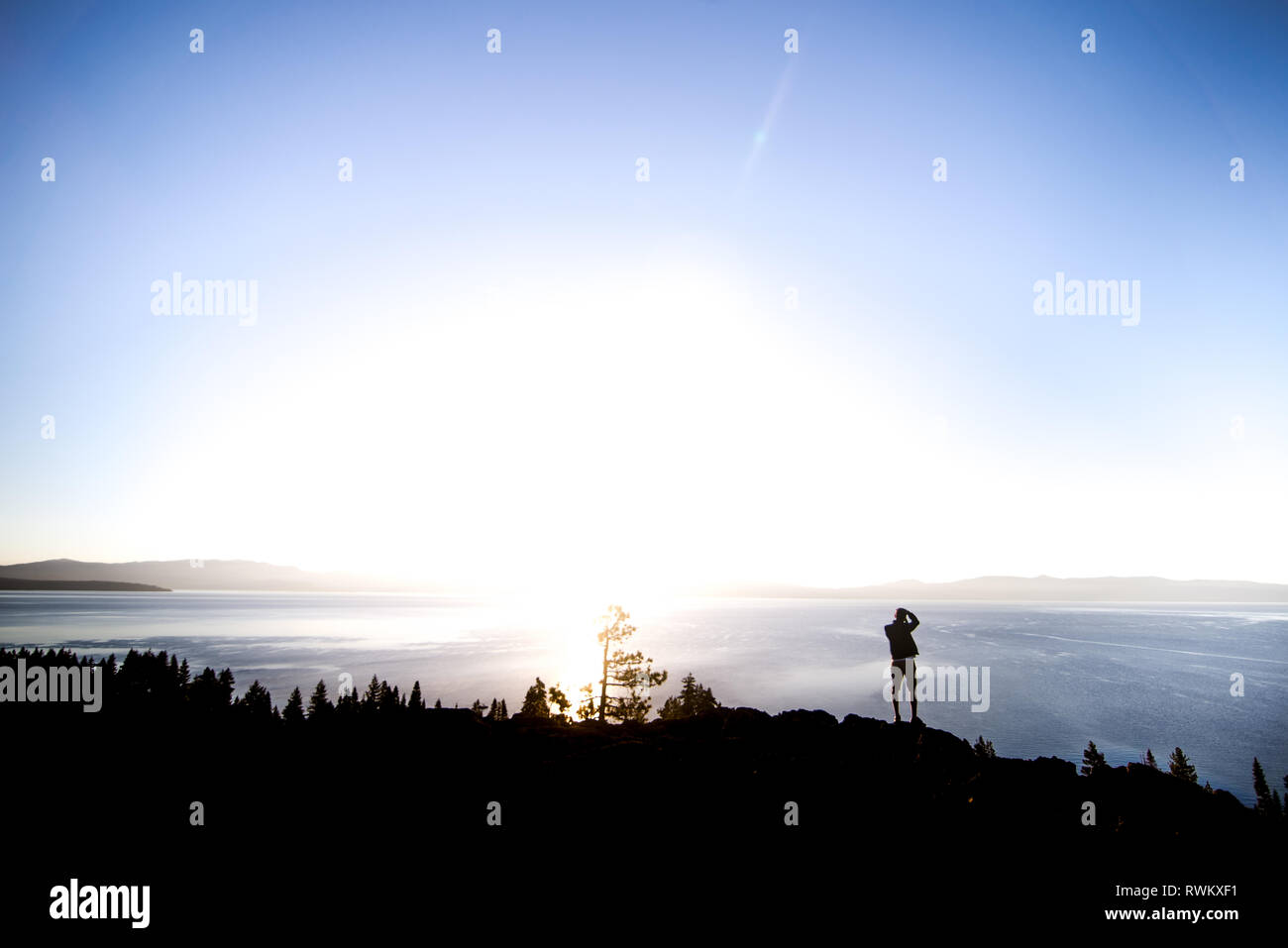 Man taking photographs at sunrise, Lake Tahoe, Tahoe City, California, United States Stock Photo