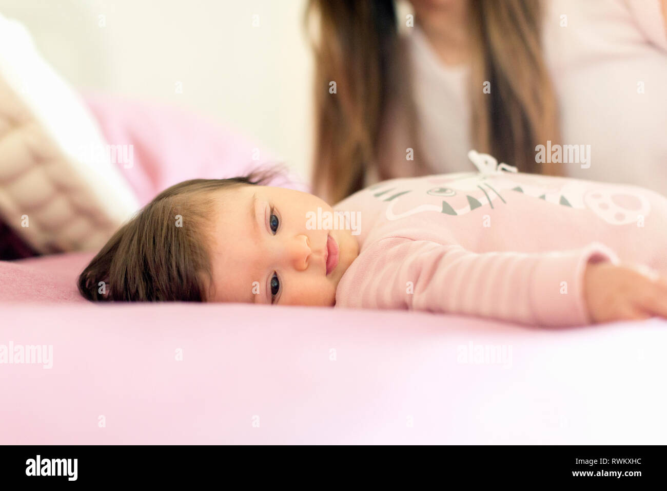 Baby girl lying down on bed Stock Photo