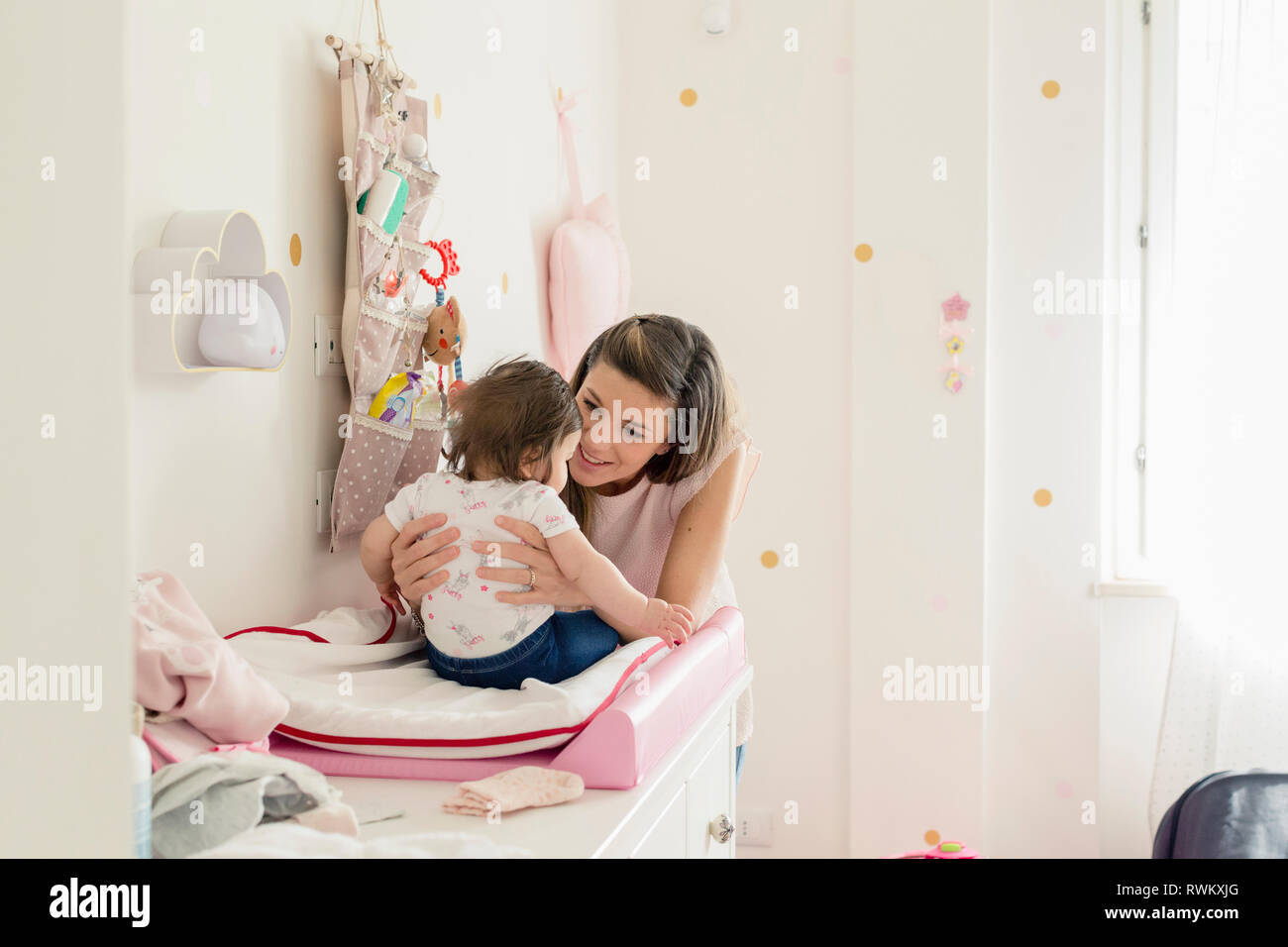 Mother talking to baby girl on changing table Stock Photo