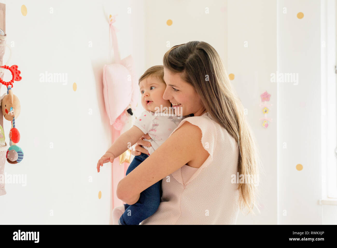 Mother hugging baby girl in room Stock Photo