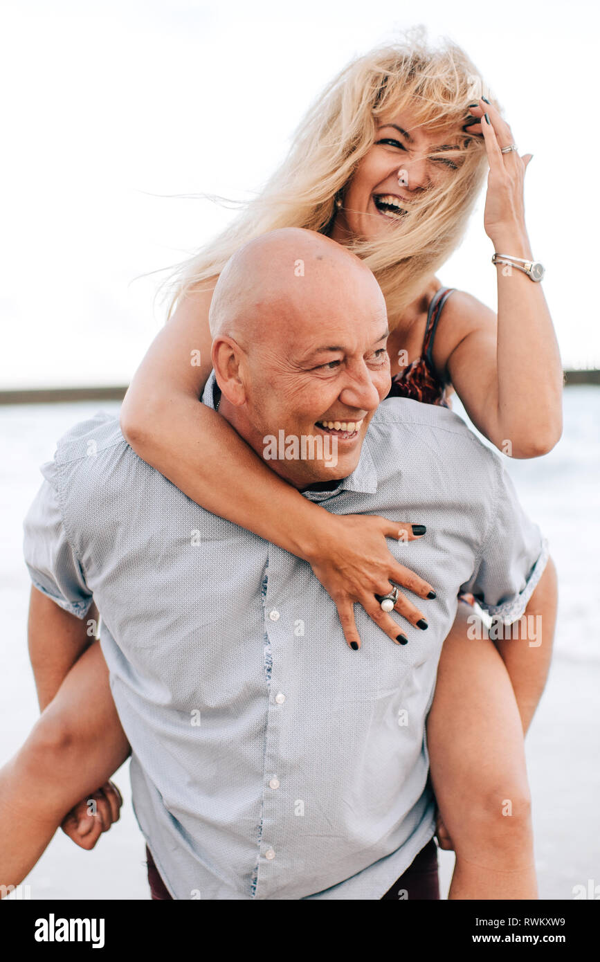 Couple playing piggyback ride on beach Stock Photo - Alamy