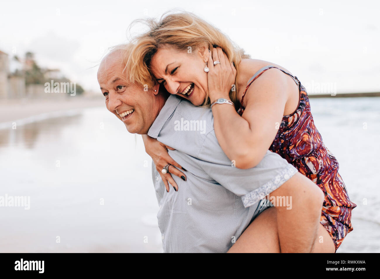 Couple playing piggyback ride on beach Stock Photo - Alamy