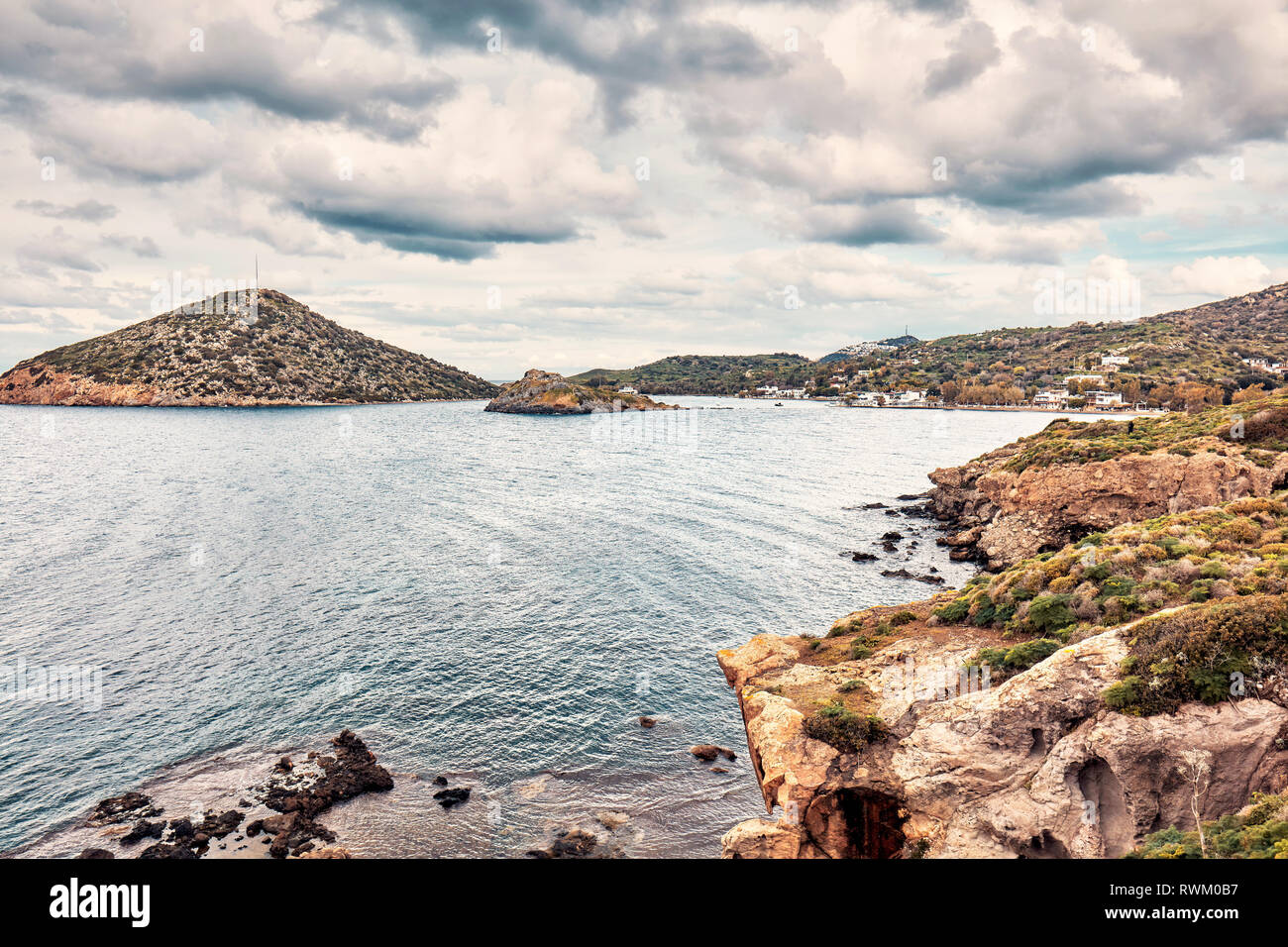 Moody view of Gumusluk bay in Bodrum, Mugla, Turkey on a cloudy winter day. Beautiful calm sea, meadow and sky landscape. Stock Photo