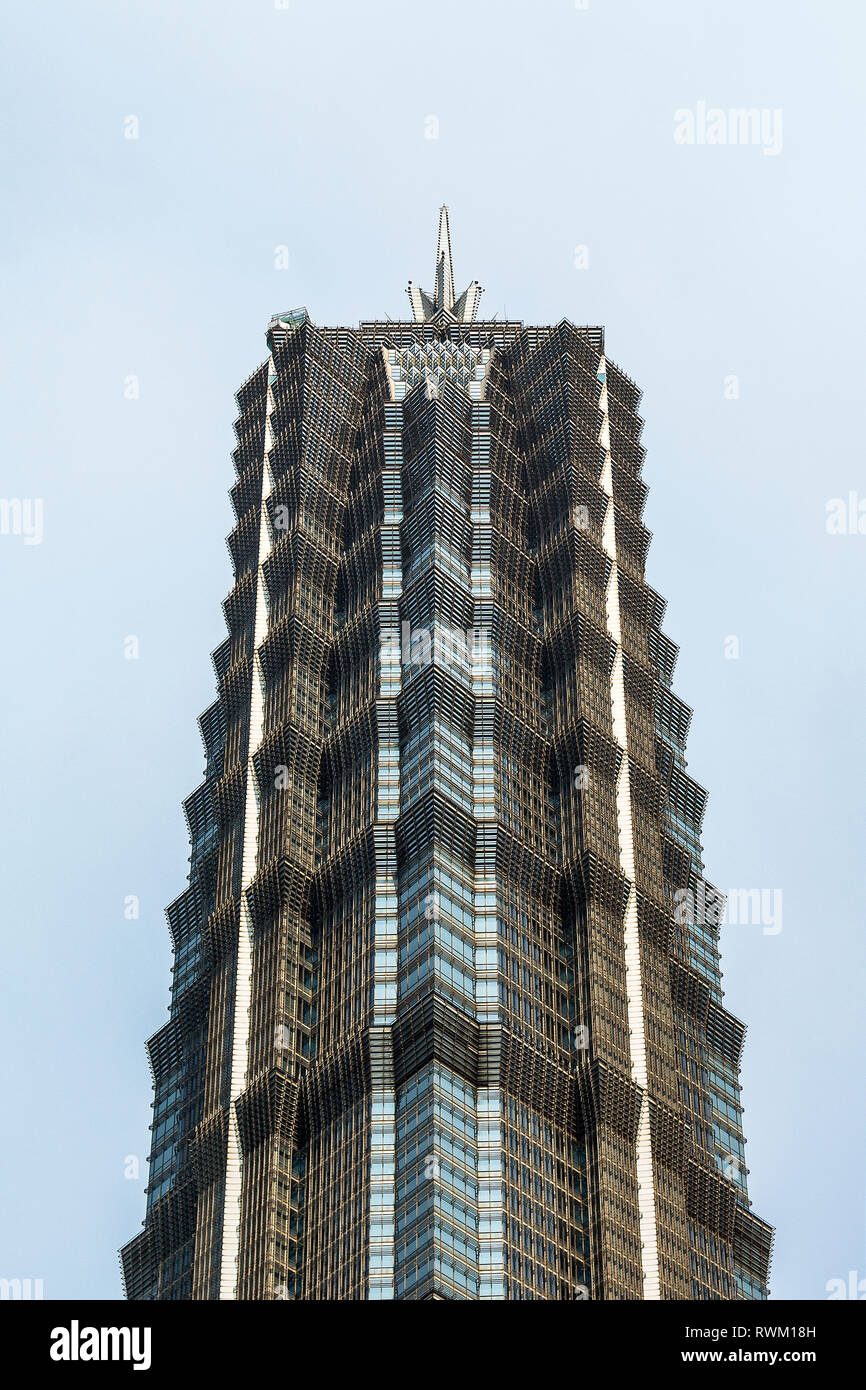 The Jin Mao Tower stands isolated against a blue sky. It's proportions revolve around the number 8, associated with prosperity in Chinese culture. Stock Photo