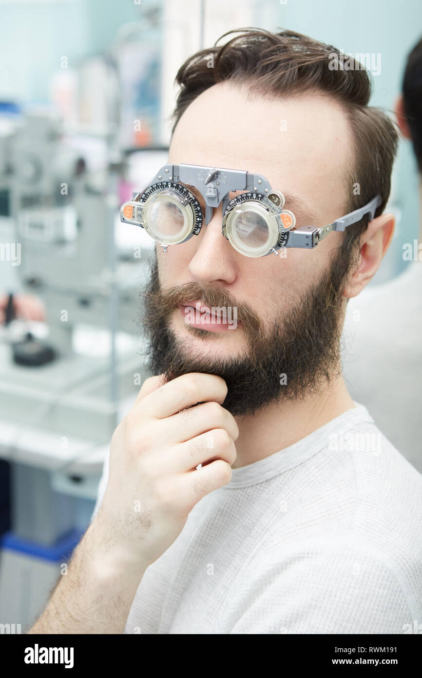 Young man with trial frames in ophthalmologist clinic Stock Photo