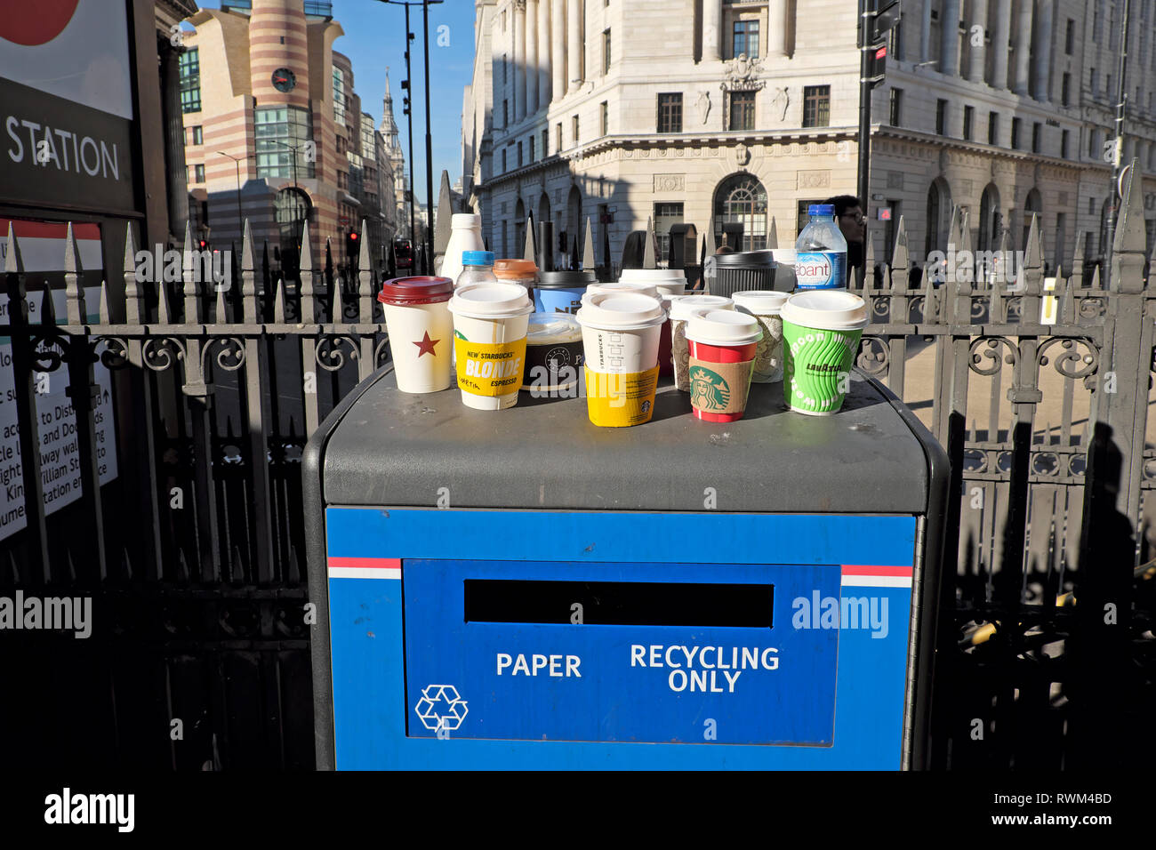 Paper and plastic empty cups and plastic bottles standing on a Paper Recycling Only waste bin Bank tube station in the City of London UK  KATHY DEWITT Stock Photo