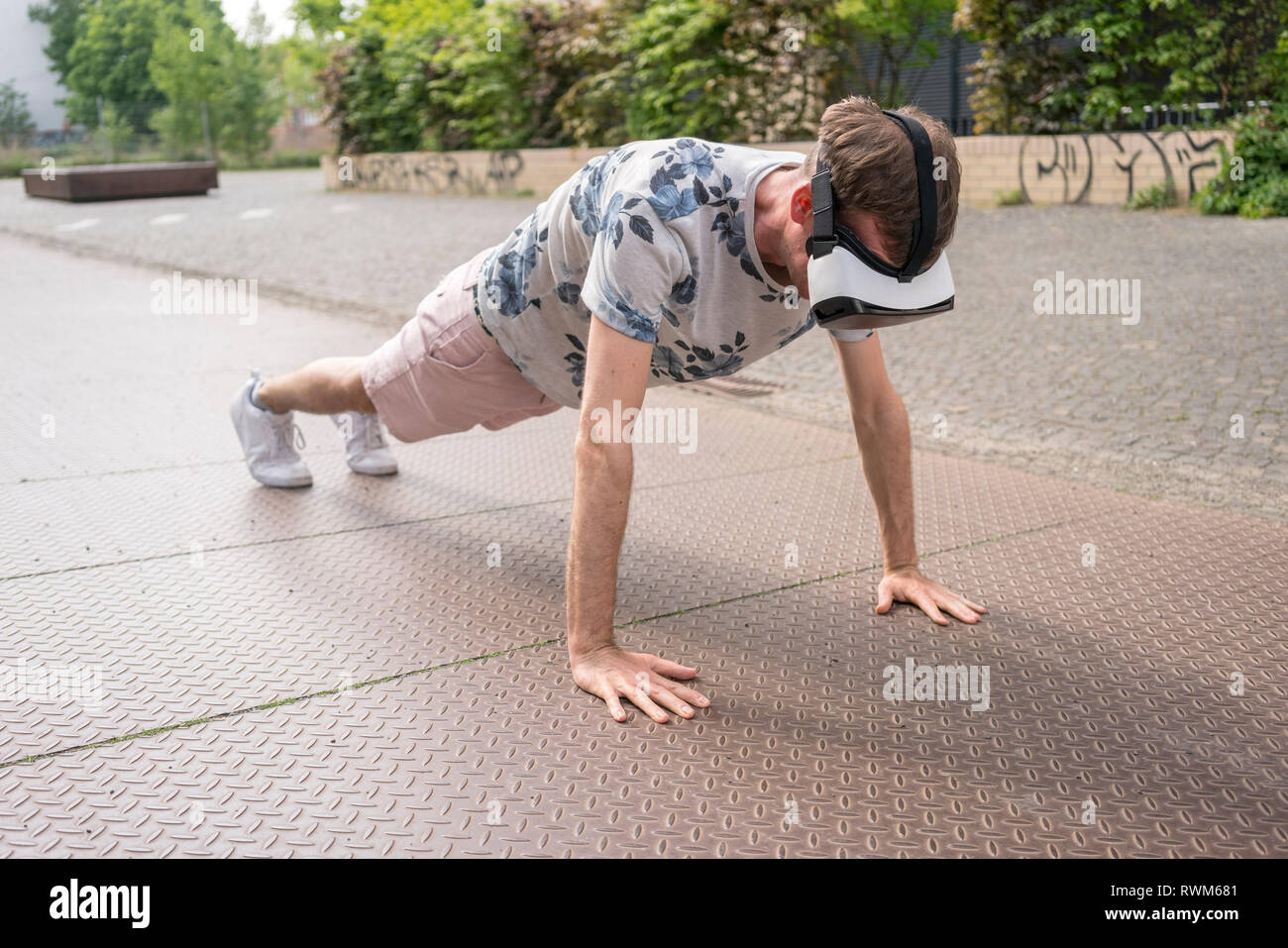 Man in push up position using virtual reality goggles, Berlin, Germany Stock Photo