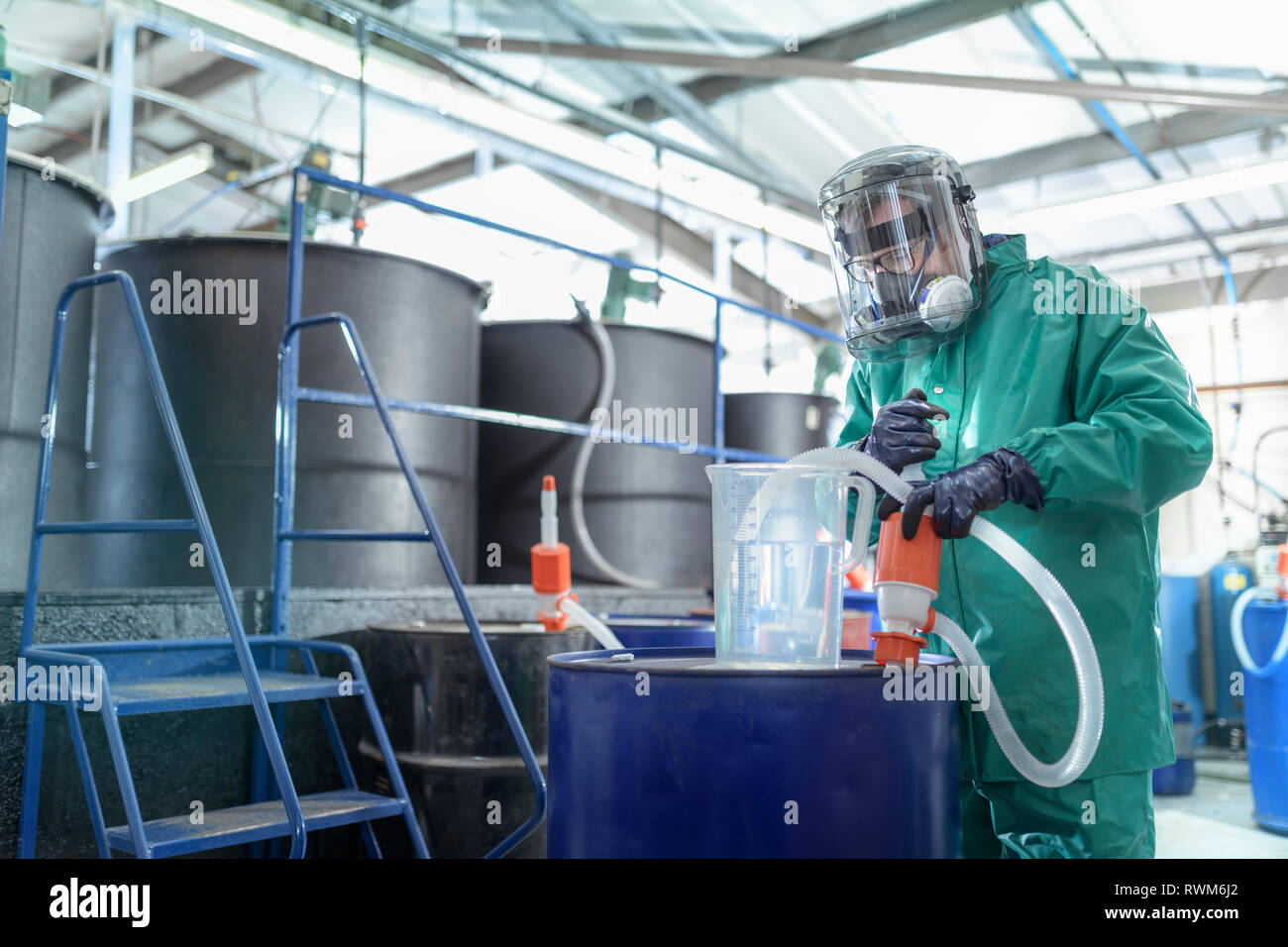 Worker filling jug with chemical in chemical factory Stock Photo
