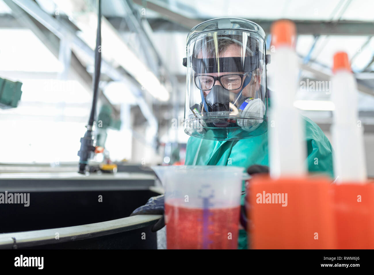 Worker pouring chemical into mixing tanks in chemical factory Stock Photo