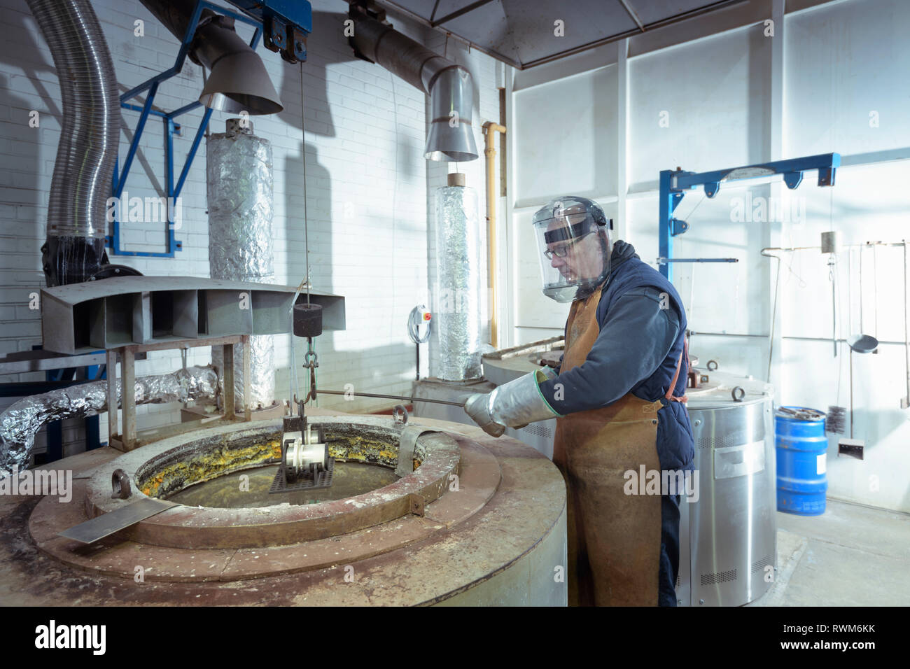 Engineer dipping components into molten salt in engineering factory Stock Photo