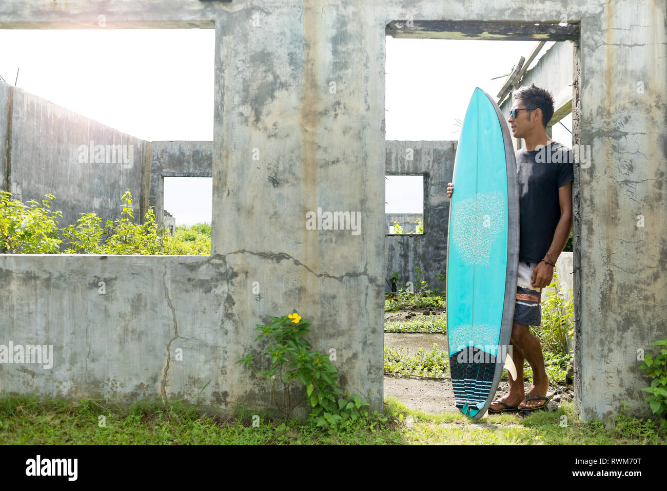 Surfer by doorway of abandoned building, Abulug, Cagayan, Philippines ...