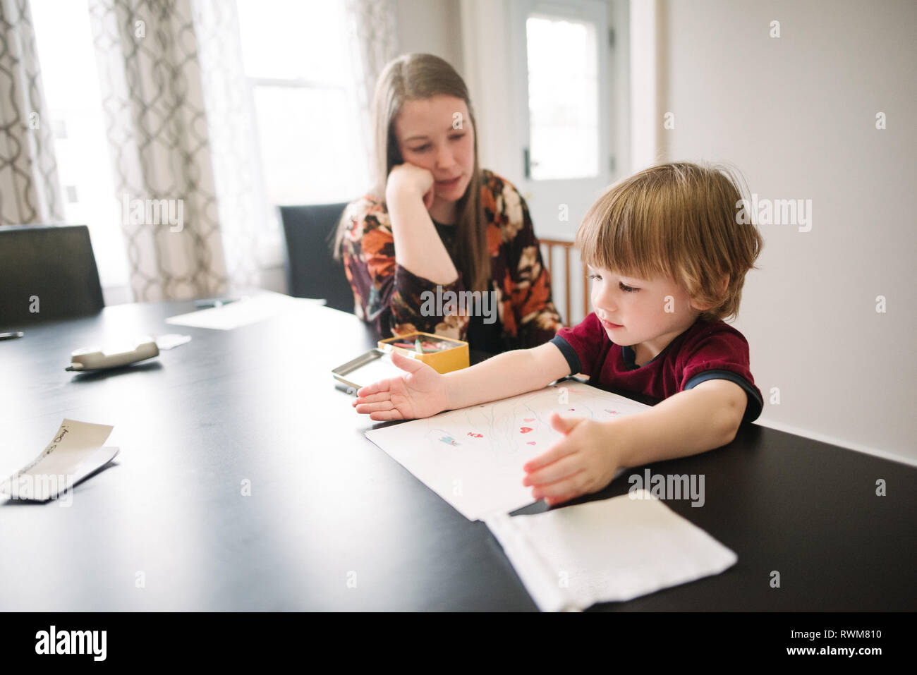 Mother watching over son learning at table Stock Photo