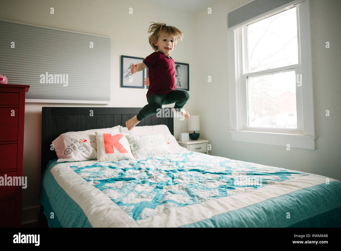 Boy jumping on bed Stock Photo