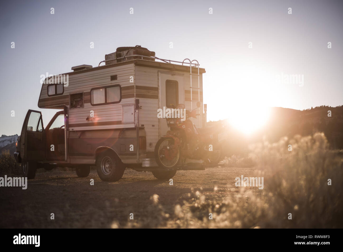 Campervan carrying touring motorcycle behind parked in desert, Sierra Nevada, Bishop, California, USA Stock Photo