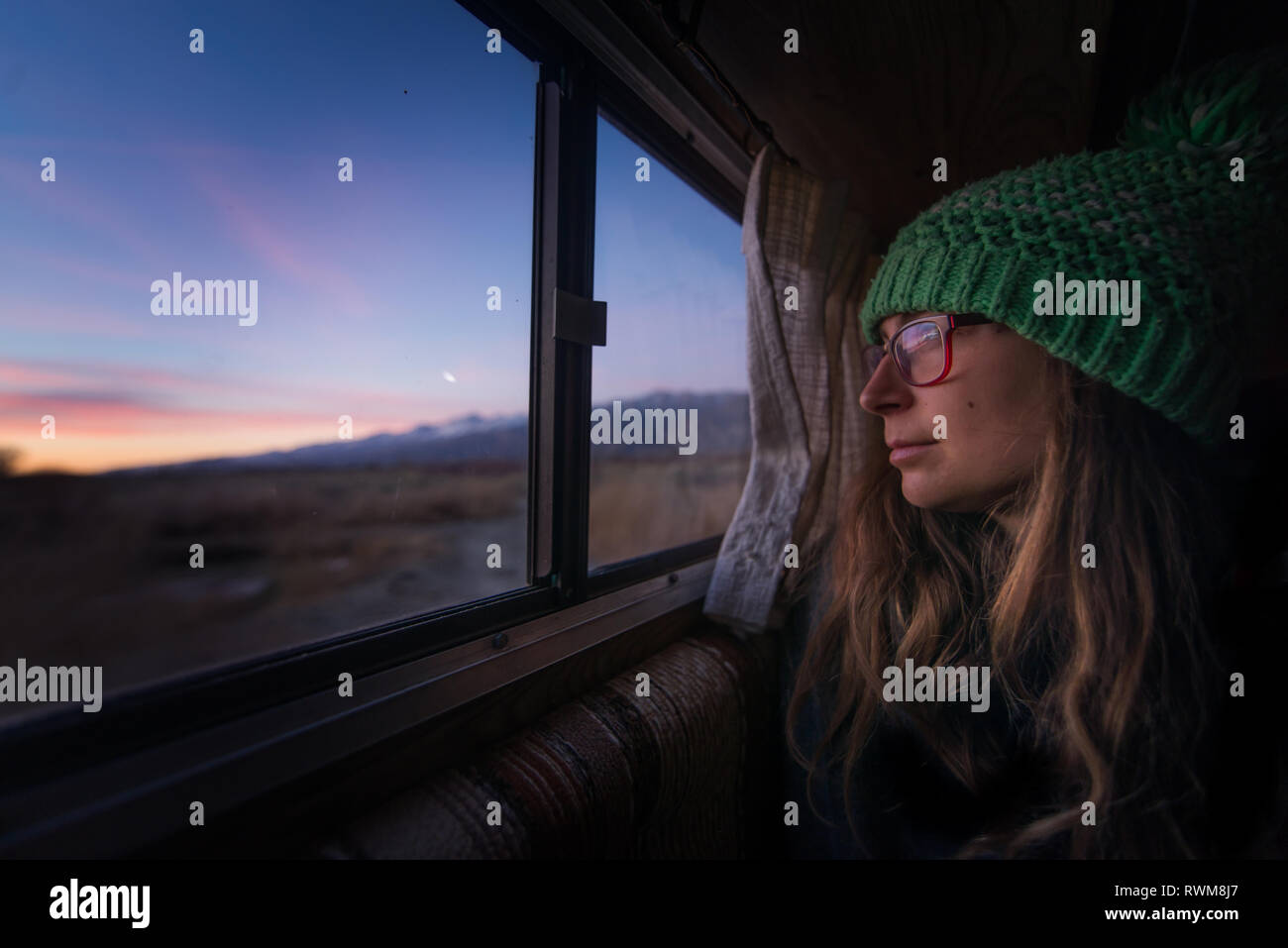 Woman keeping warm inside campervan in desert, Sierra Nevada, Bishop, California, USA Stock Photo