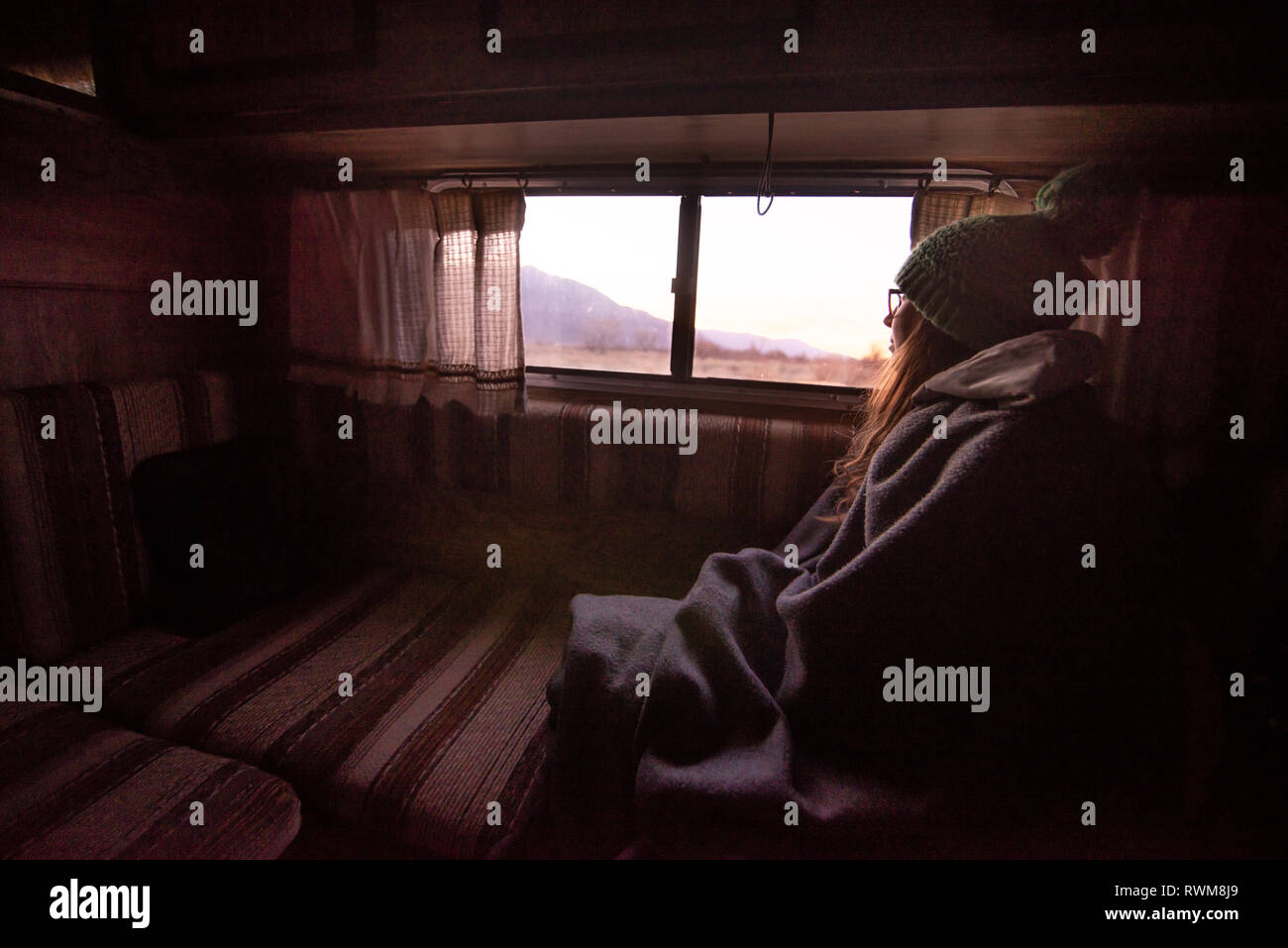 Woman keeping warm inside campervan in desert, Sierra Nevada, Bishop, California, USA Stock Photo