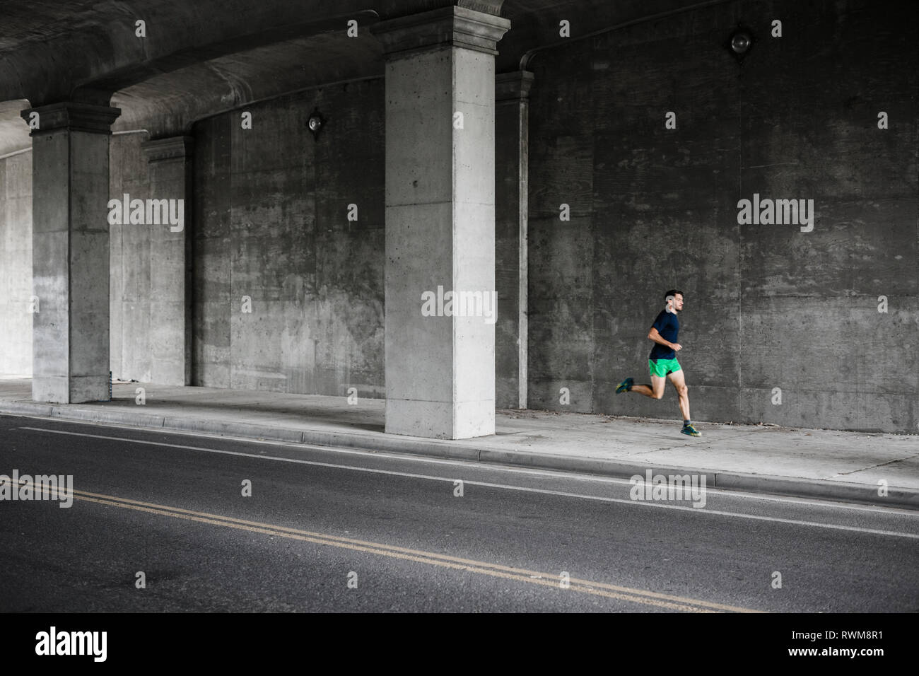 Young male runner running through underpass Stock Photo