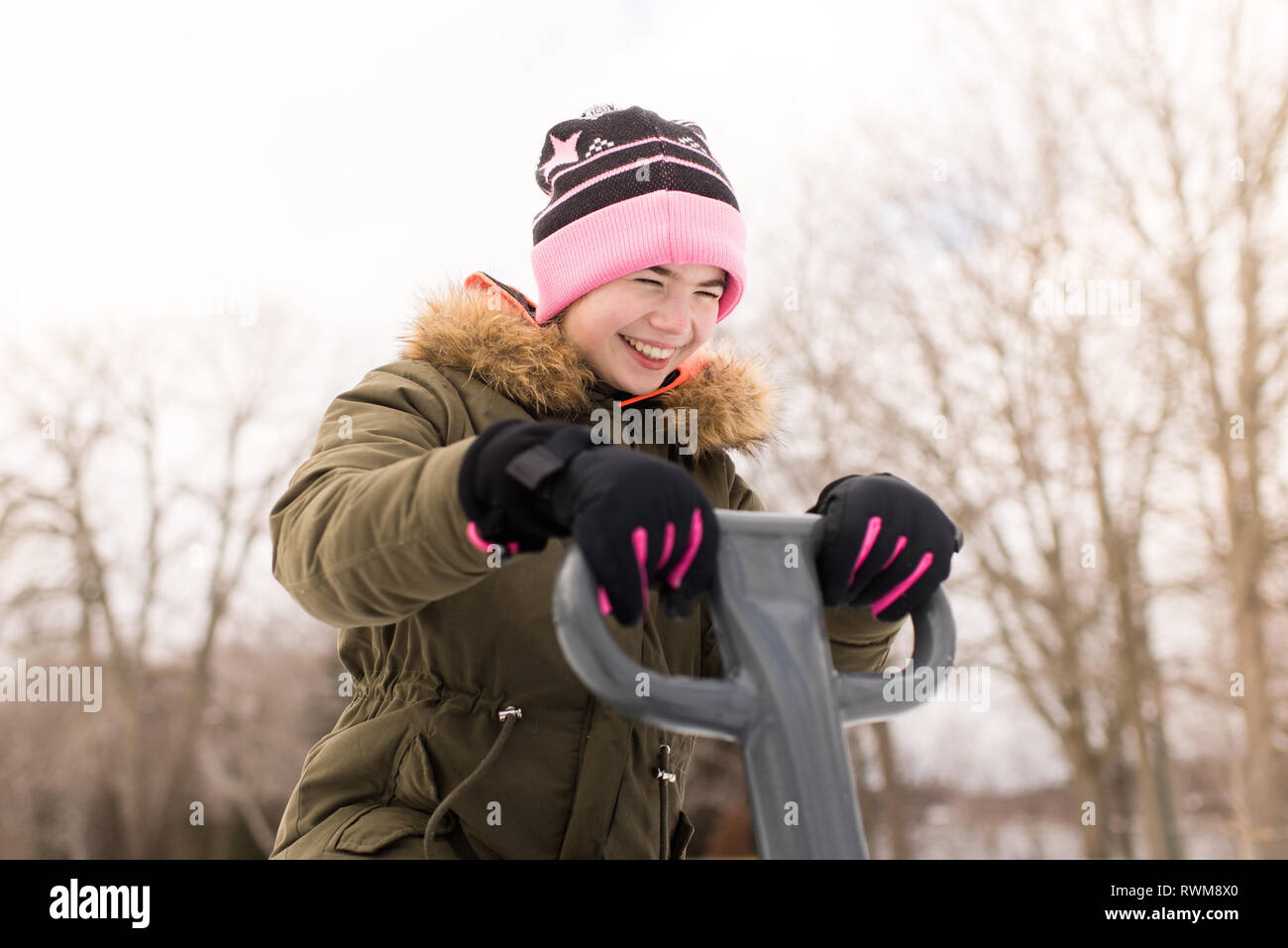 Girl in knit hat laughing on playground equipment Stock Photo