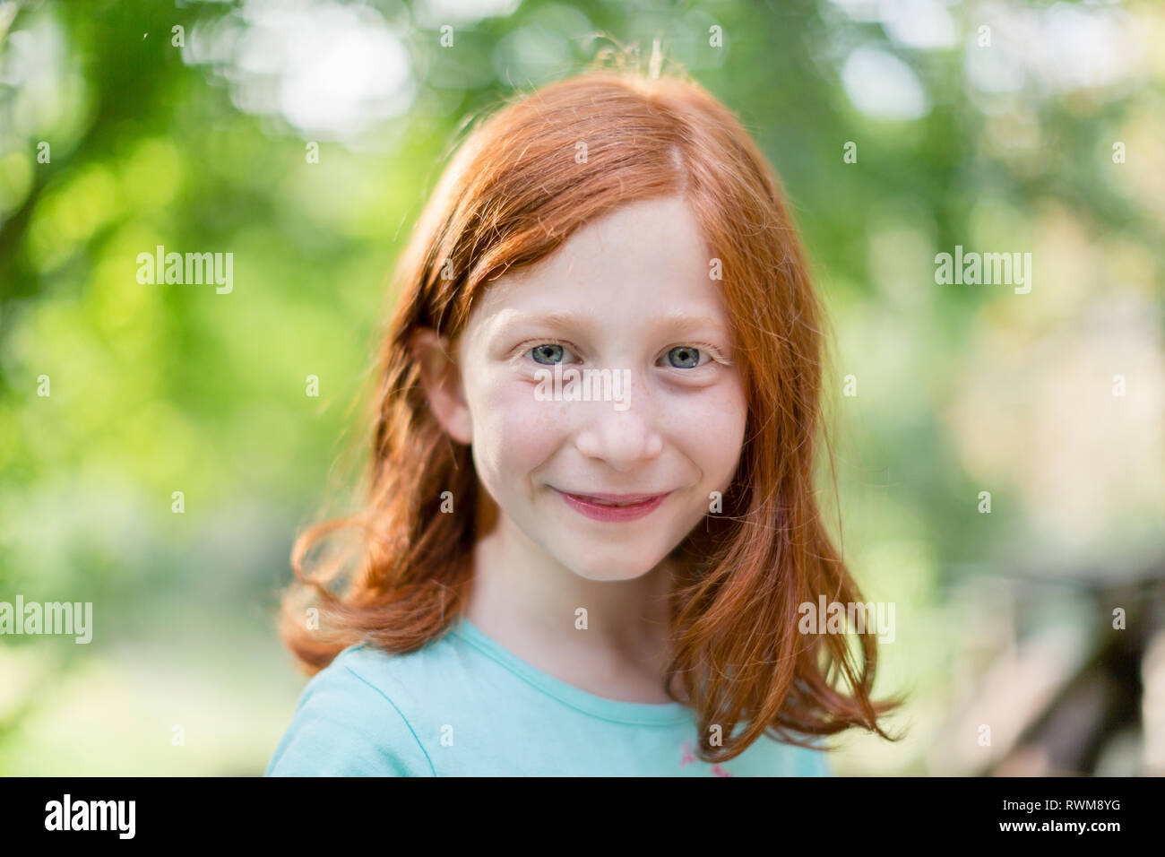 Red haired girl in garden, head and shoulder portrait Stock Photo