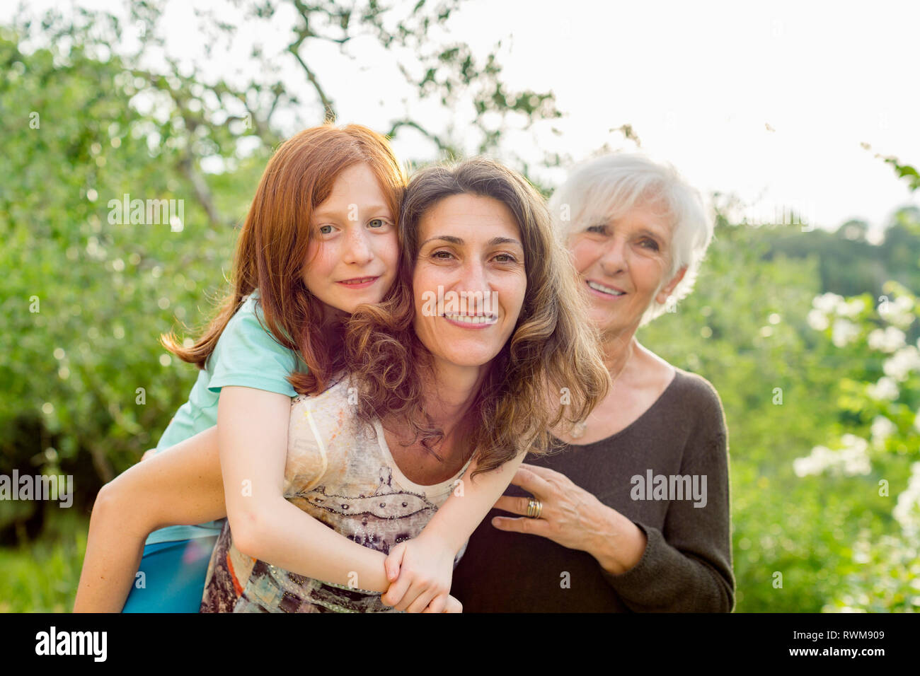Girl getting piggyback with mother and grandmother in garden, portrait Stock Photo