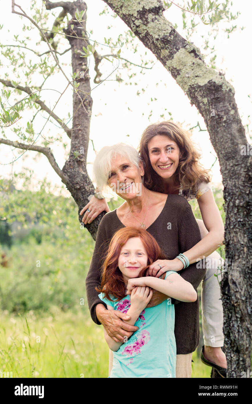Girl by garden tree with mother and grandmother, portrait Stock Photo