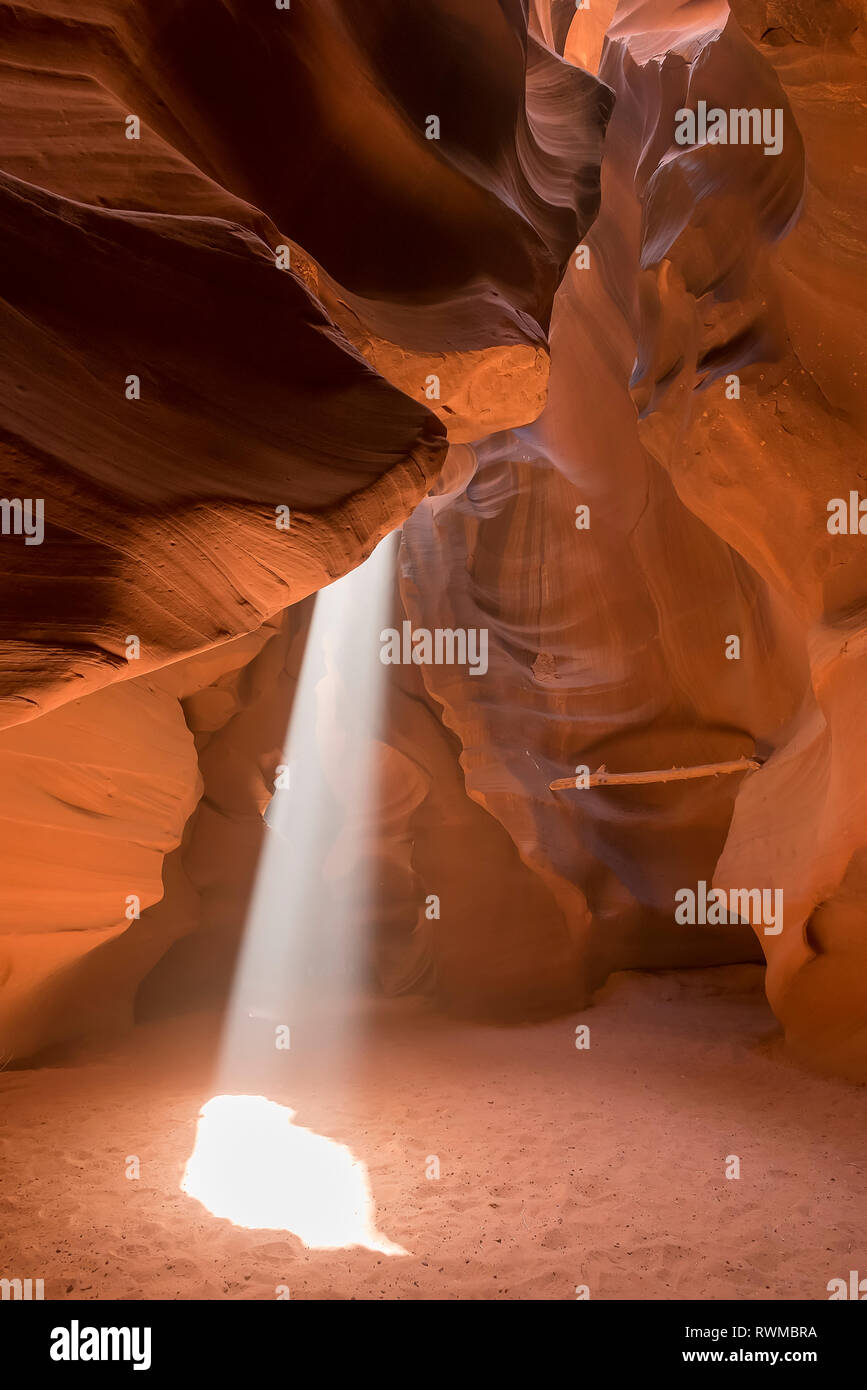 Sunlight streams through a natural hole in the sandstone to the sand below, Upper Antelope Canyon; Arizona, United States of America Stock Photo