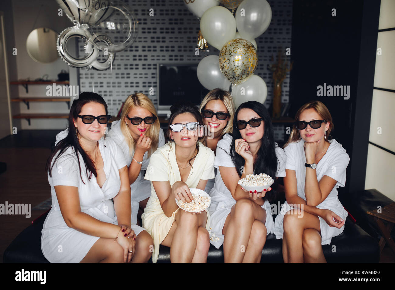 Bridesmaids and pretty bride in glasses eating popcorn Stock Photo