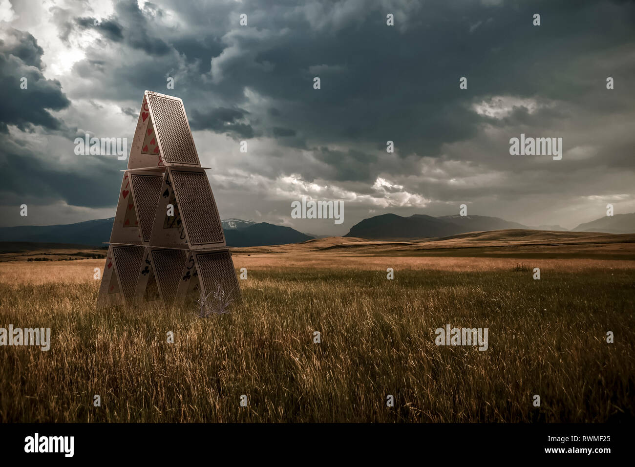 Playing cards set up in a grass field under a stormy sky, composite image Stock Photo