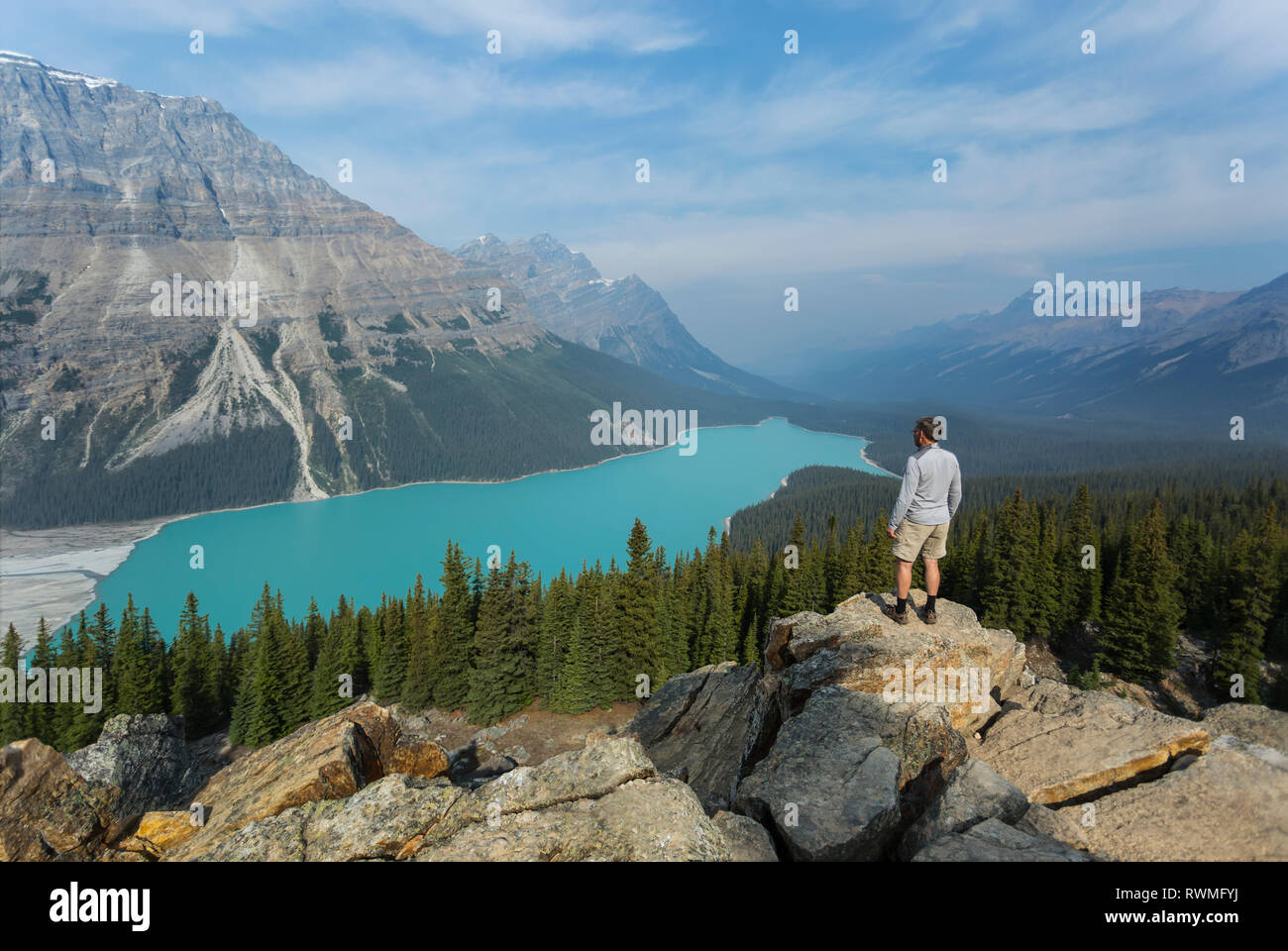 A man stands on a rock ridge overlooking the stunning turquoise water of Peyto Lake in Banff National Park; Alberta, Canada Stock Photo