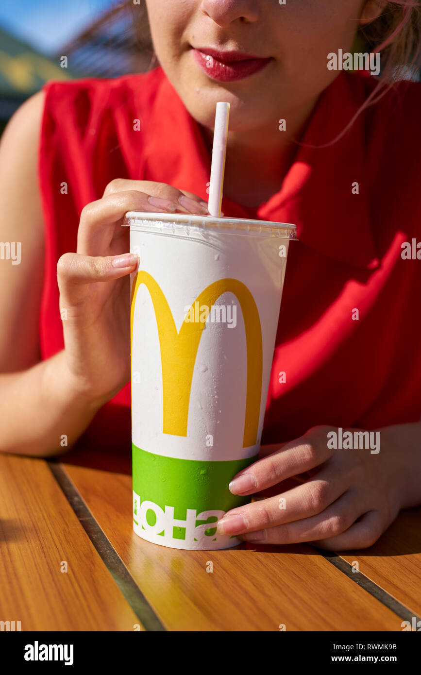 KALININGRAD, RUSSIA - CIRCA SEPTEMBER, 2018: young woman with paper cup of Coca-Cola at McDonald's restaurant. Stock Photo