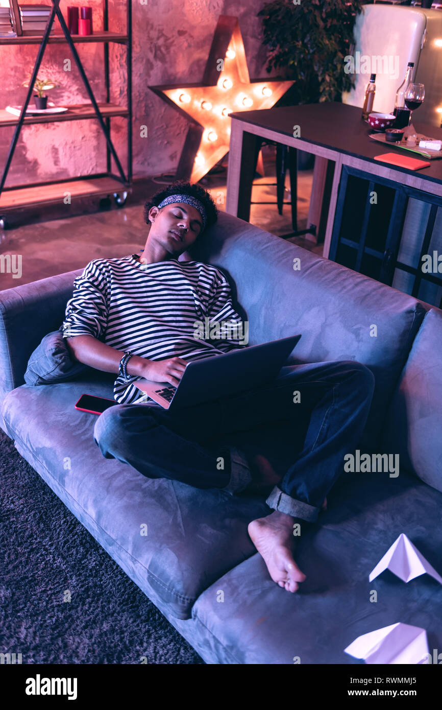 Adult Boy Falling Asleep On A Couch While Doing Boring Homework