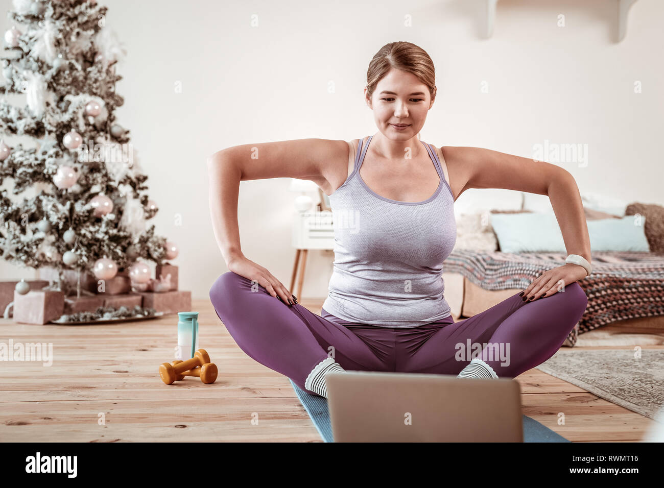 Resolute appealing woman recreating yoga posture from video lesson Stock Photo