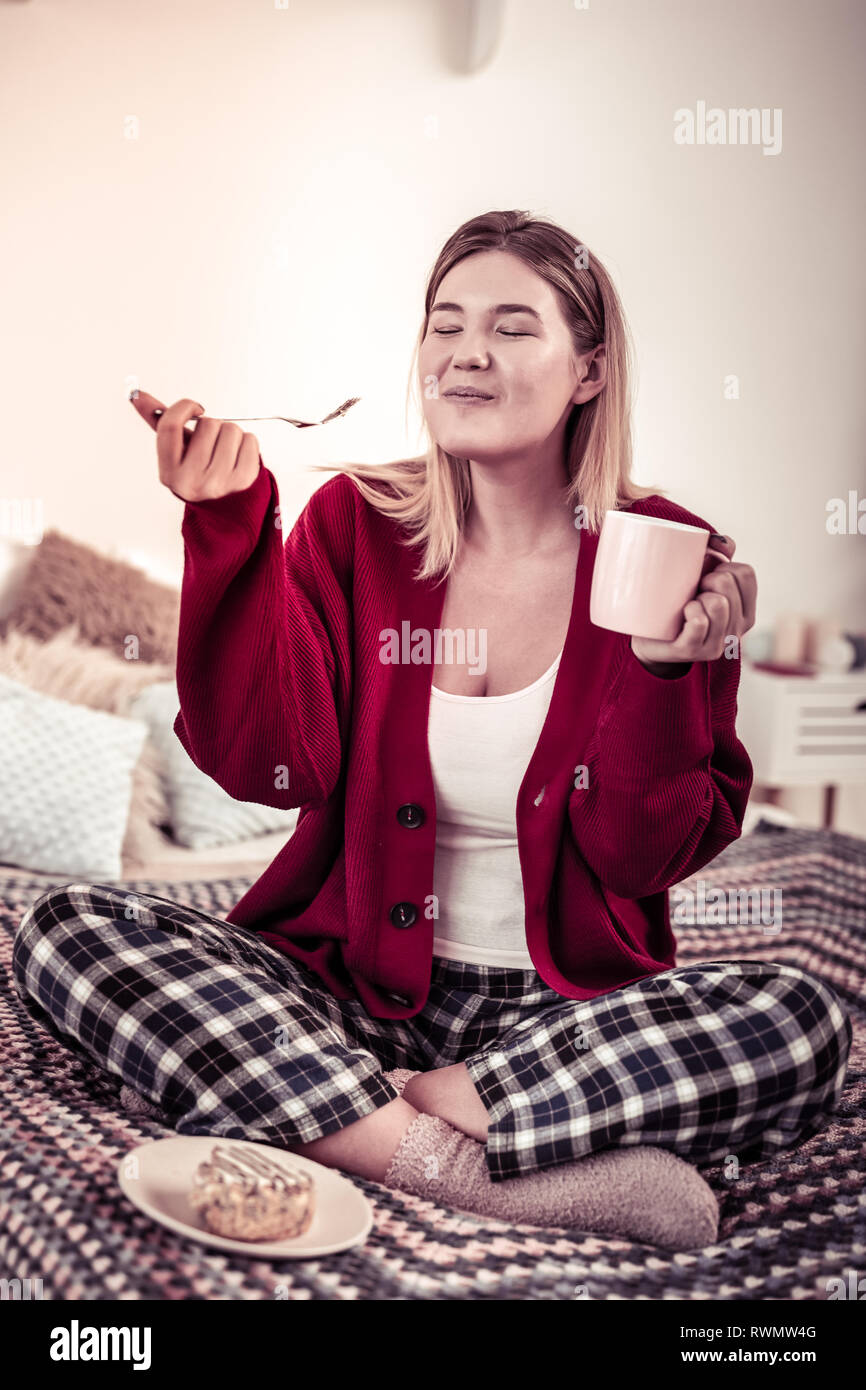 Satisfied happy woman being extremely pleasant with taste of cake Stock Photo