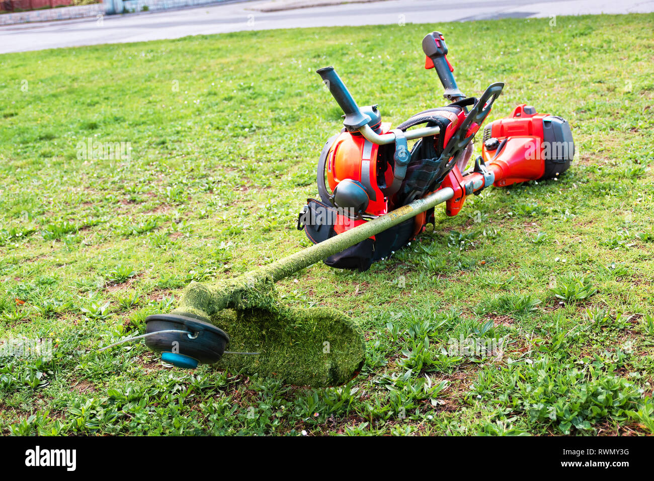 Grass cutter / Brush cutter, safety helmet and other equipment lay on the lawn Stock Photo