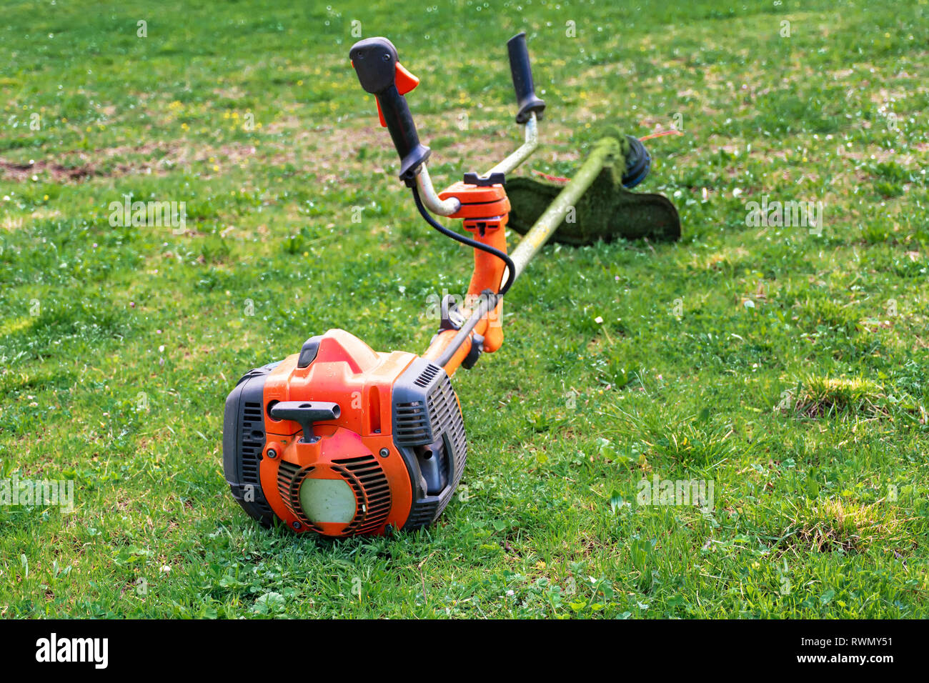 Grass cutter / brush cutter for trimming overgrown grass lay on the lawn Stock Photo