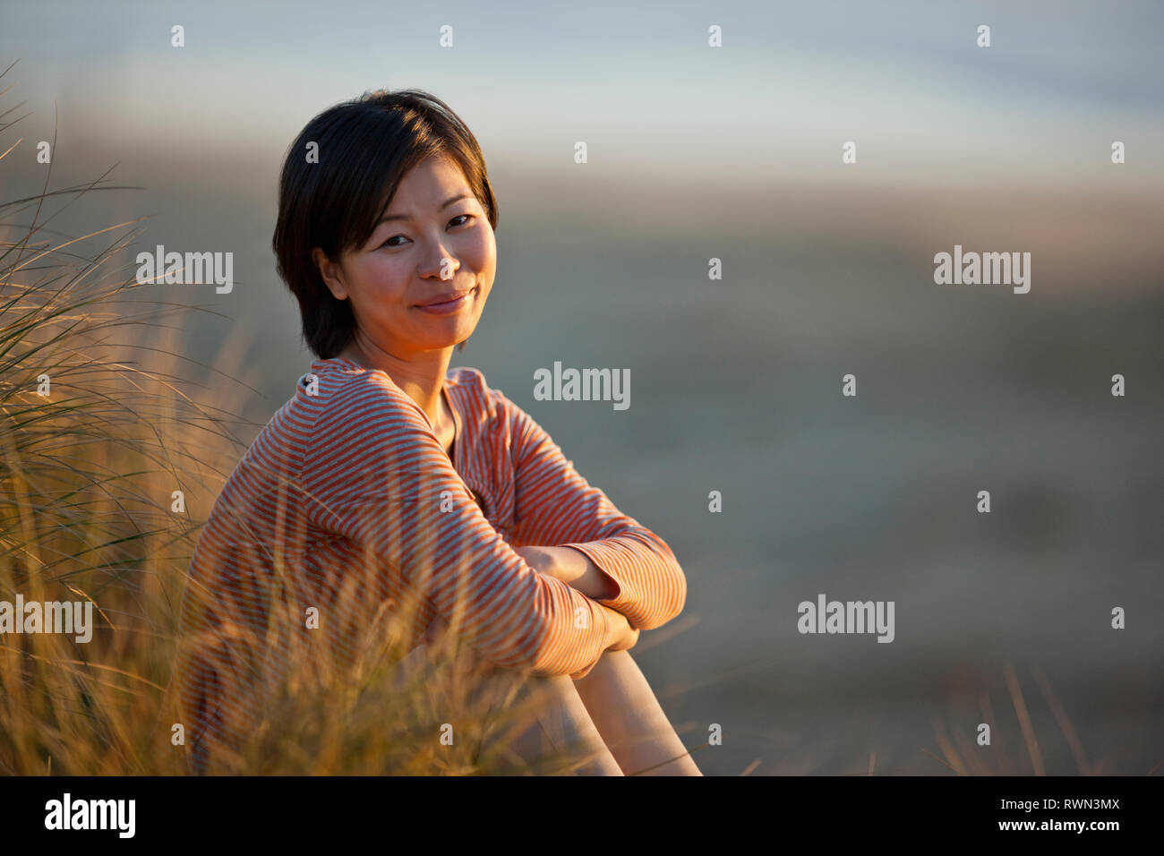 Portrait of a content young woman sitting on a beach. Stock Photo