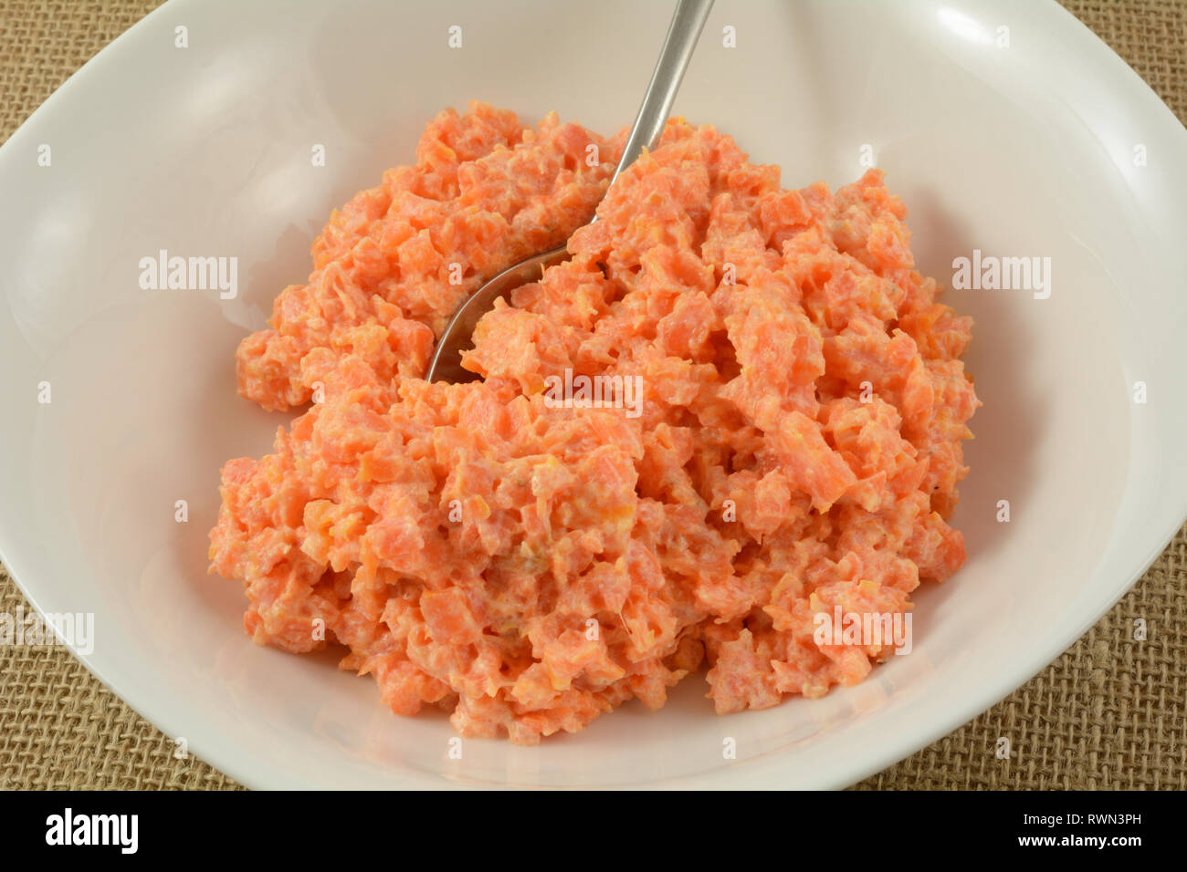 Close up of mashed carrots in serving bowl with serving spoon Stock Photo