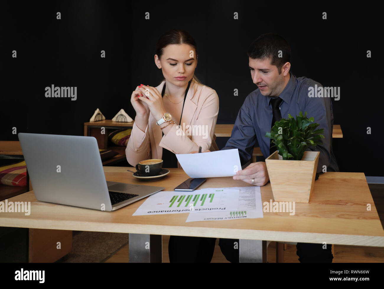 Couple doing accounts in a small cafeteria. Man and woman working on laptop in cafe Stock Photo