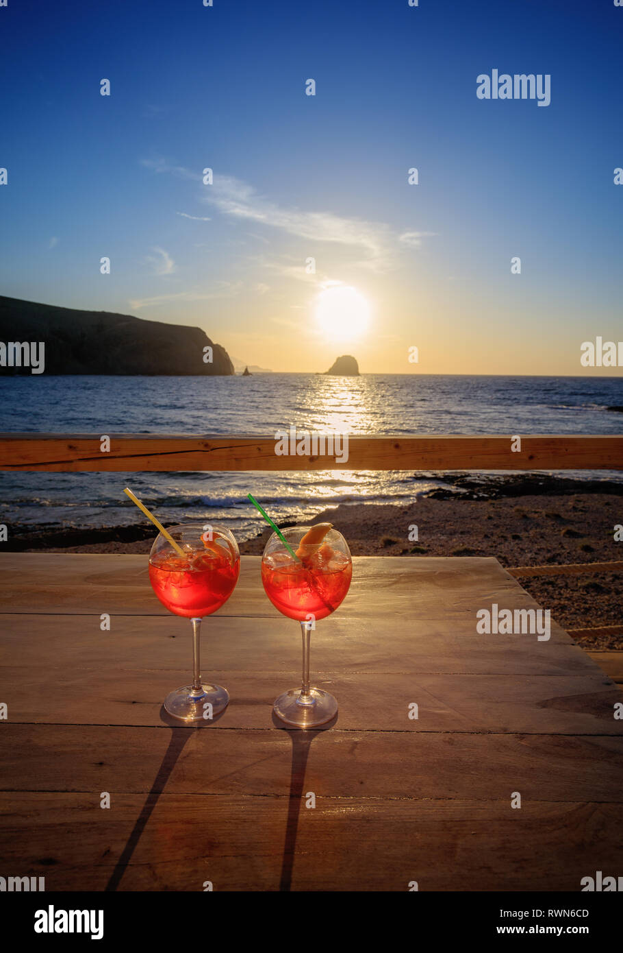 Aperol Spritz (aperitif cocktail consisting of prosecco, Aperol and soda water). Two glasses on a table on the beach at sunset Stock Photo