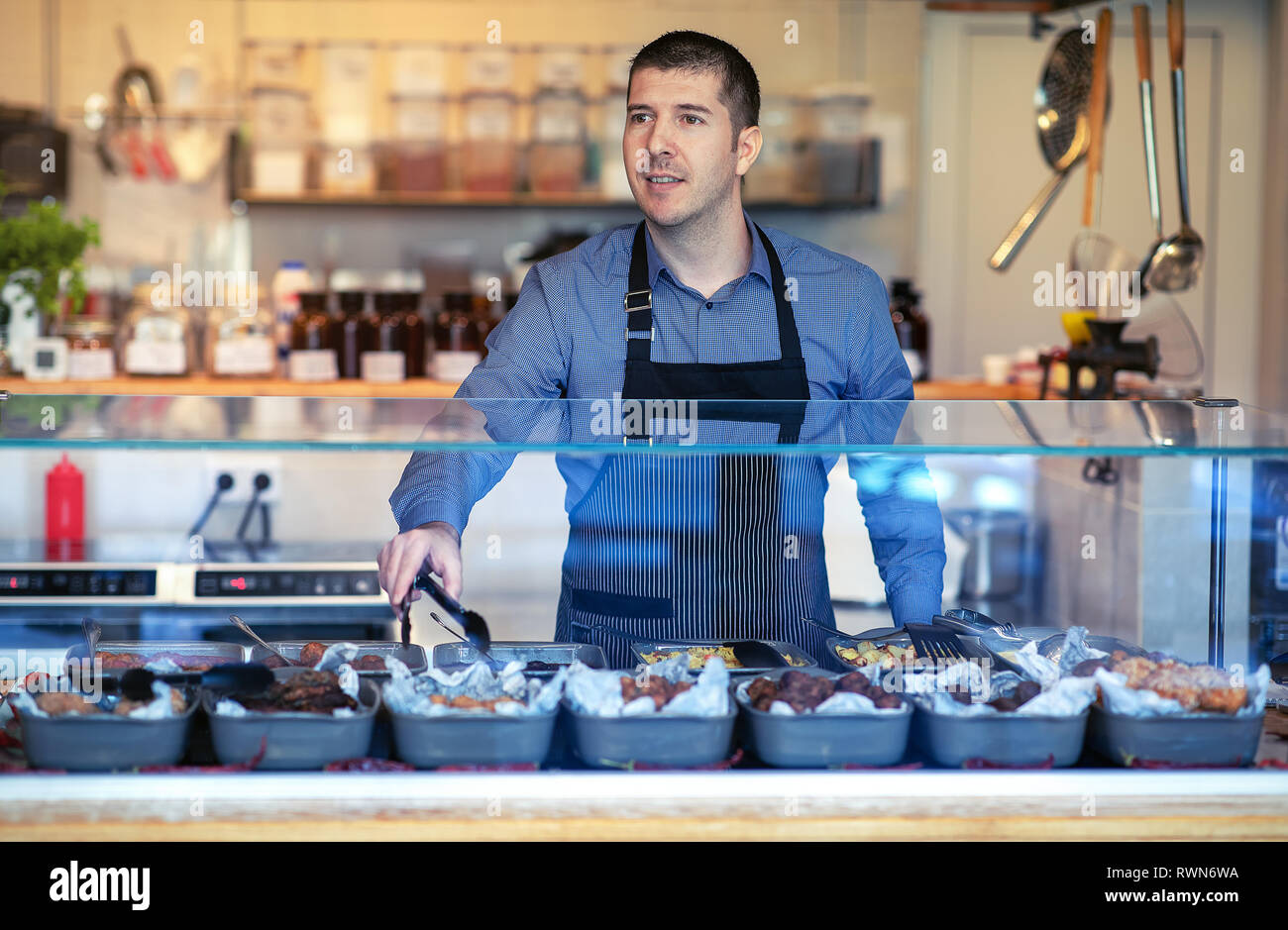 Employee working with kebab, vegetables and oriental food at bistro. Employee wearing apron at counter Stock Photo