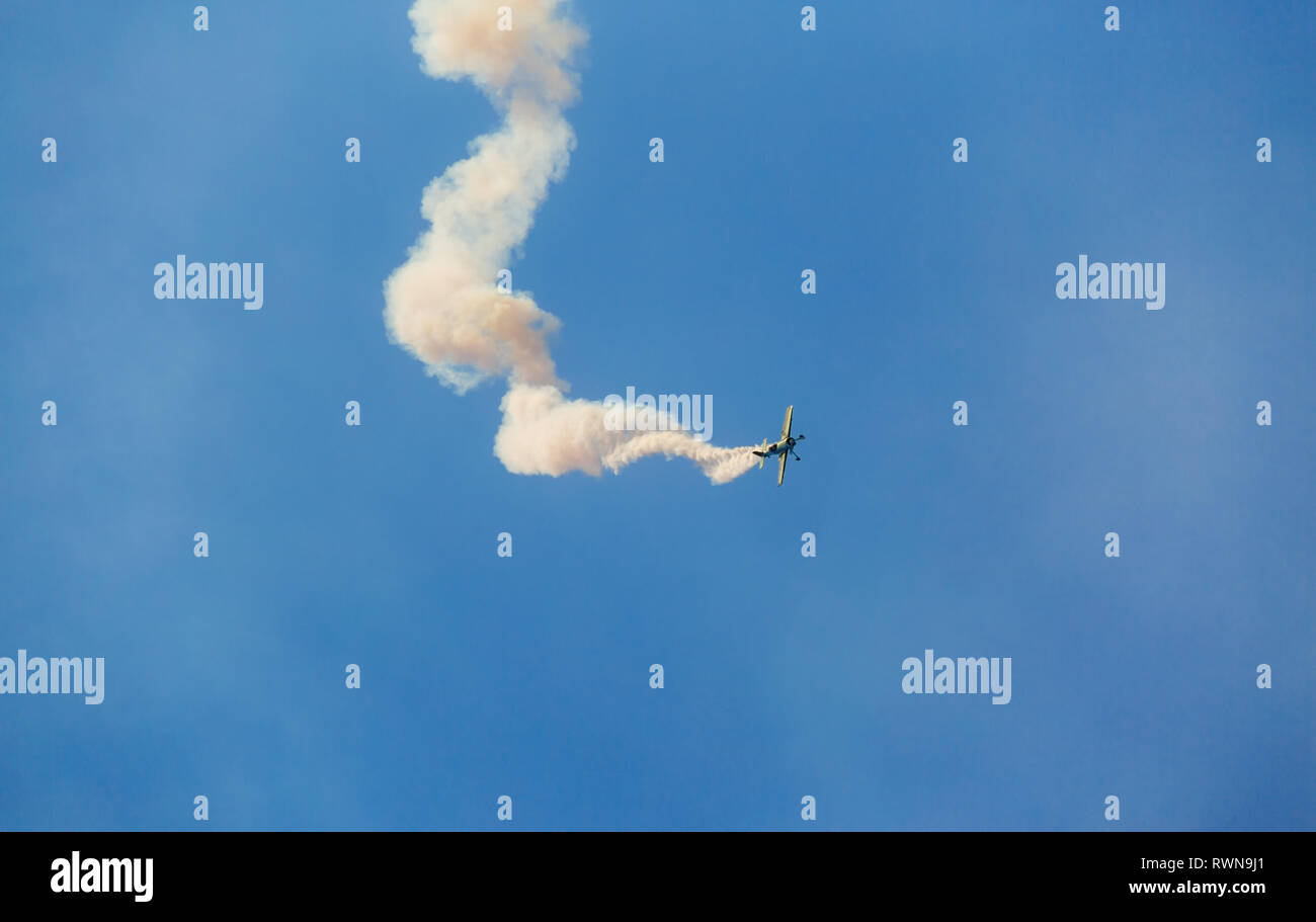 Unidentifiable single airplane performing acrobatic flight on blue sky ...