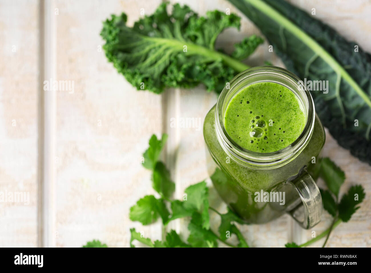 Green juice made from kale and cilantro on a white wooden surface with copy space Stock Photo