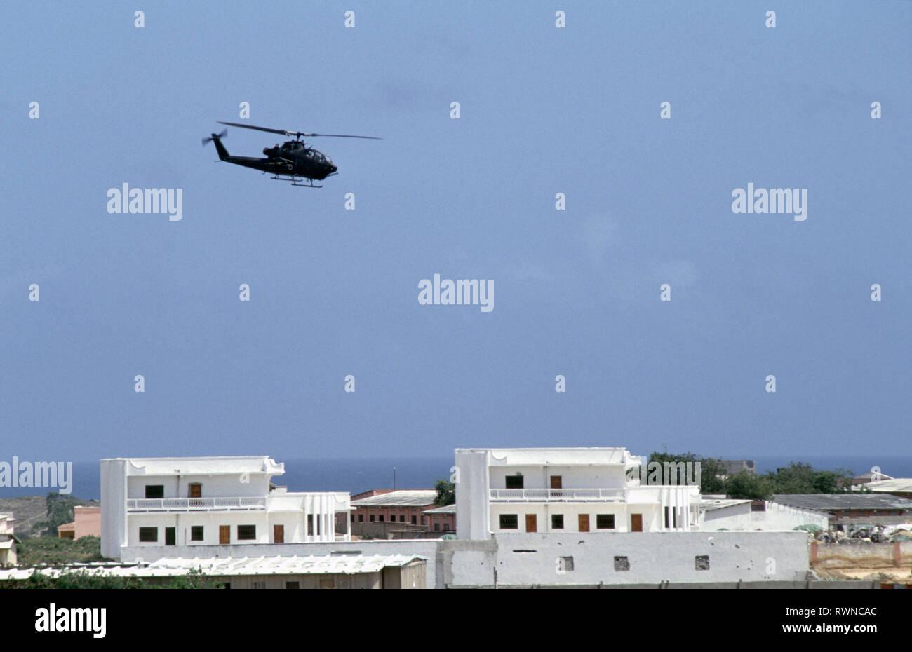 20th October 1993 A U.S. Army Bell AH-1 Cobra attack helicopter patrols low above the rooftops of Mogadishu, Somalia. Stock Photo