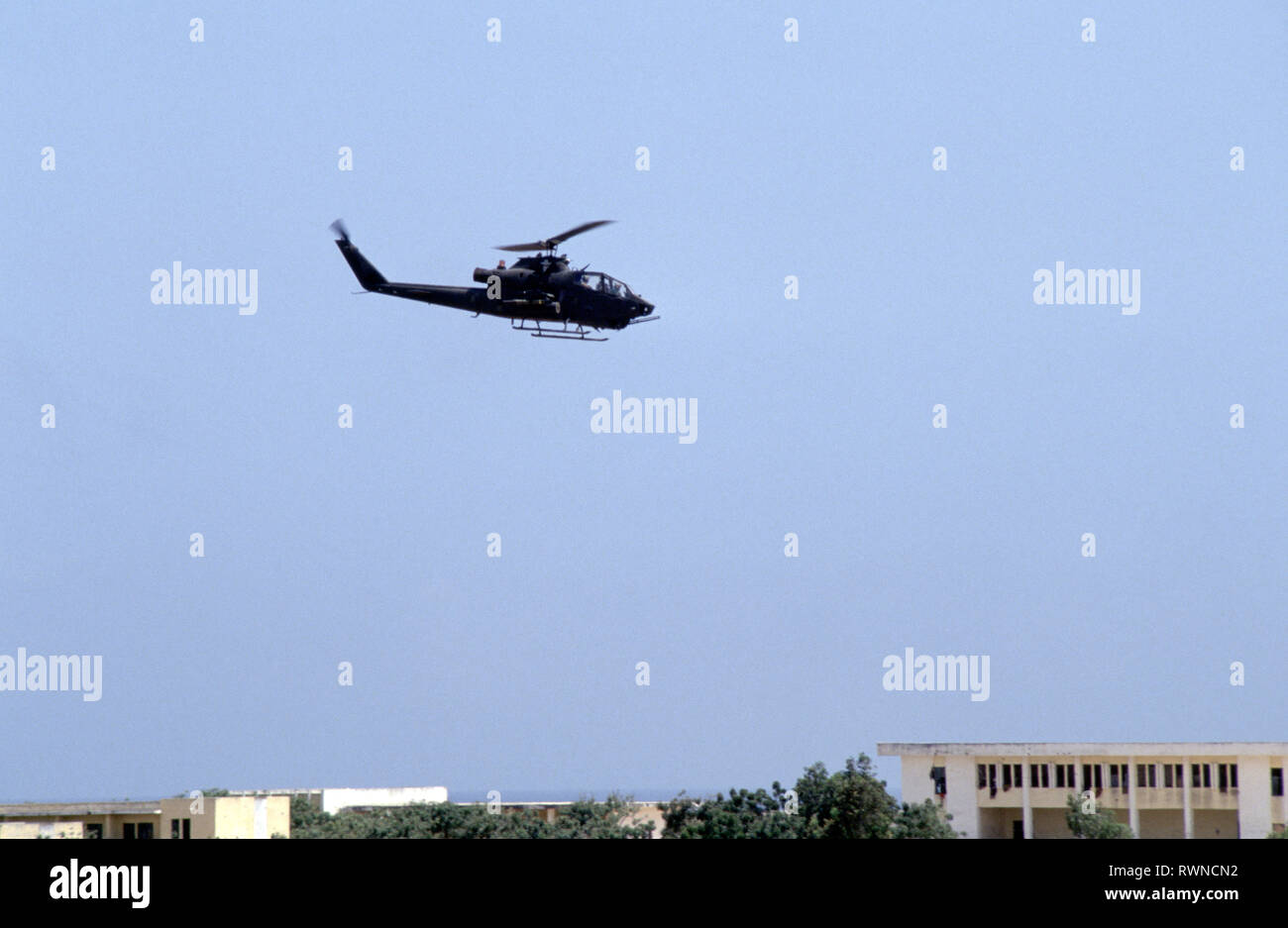 20th October 1993 A U.S. Army Bell AH-1 Cobra attack helicopter patrols low above the rooftops of Mogadishu, Somalia. Stock Photo
