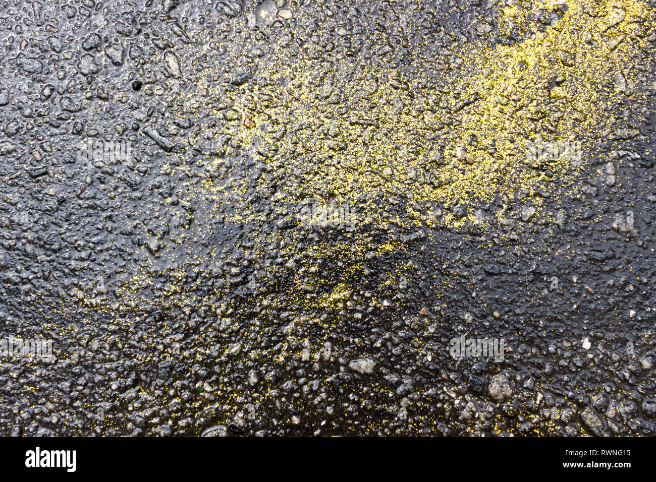 Wet asphalt floor with yellow glitter diluted during Carnival. Rio de Janeiro, Brazil. 2019 Stock Photo