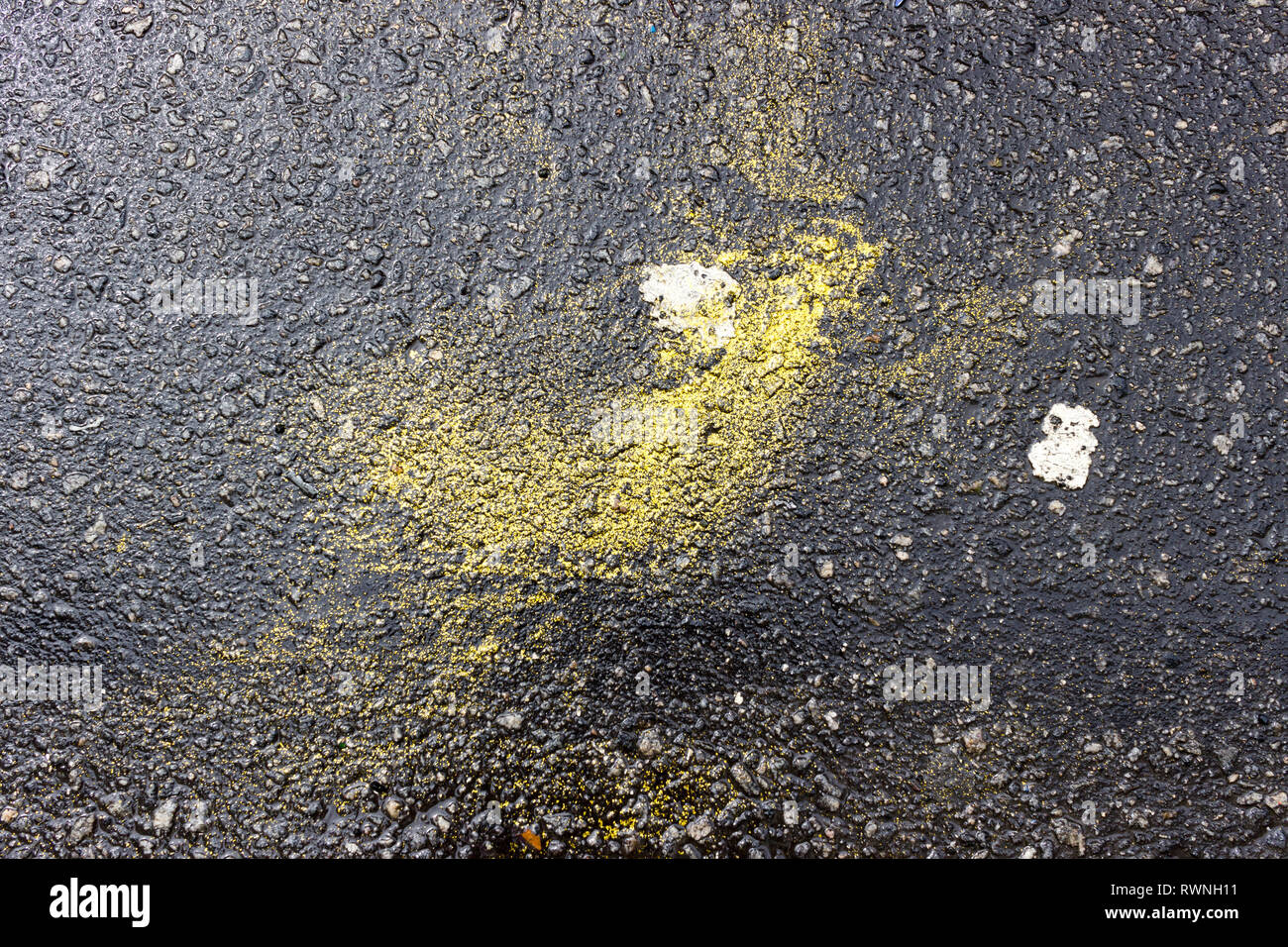Wet asphalt floor with yellow glitter diluted during Carnival. Rio de Janeiro, Brazil. 2019 Stock Photo