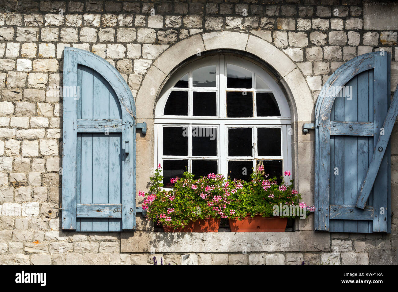 Close-up of wooden shutters on an arched window on a stone building with flower boxes; Namur, Belgium Stock Photo