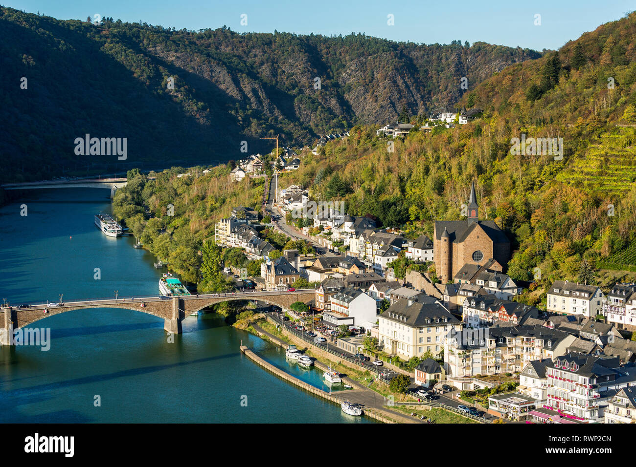 High view of riverside village with stone church and steep hillside ...
