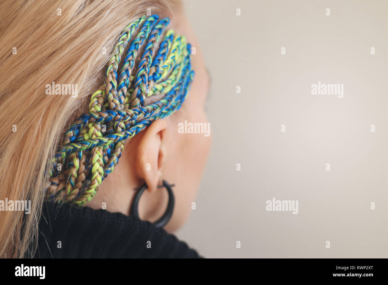 blue hair tightly braided on the temple of the girl, the background for the inscriptions beauty salon Stock Photo